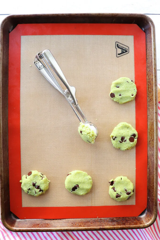 Overhead view of raw gluten free matcha cookies on a silicone liner in a pan