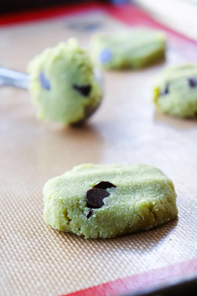 Front closeup view of raw gluten free matcha cookies on a silicone liner in a pan