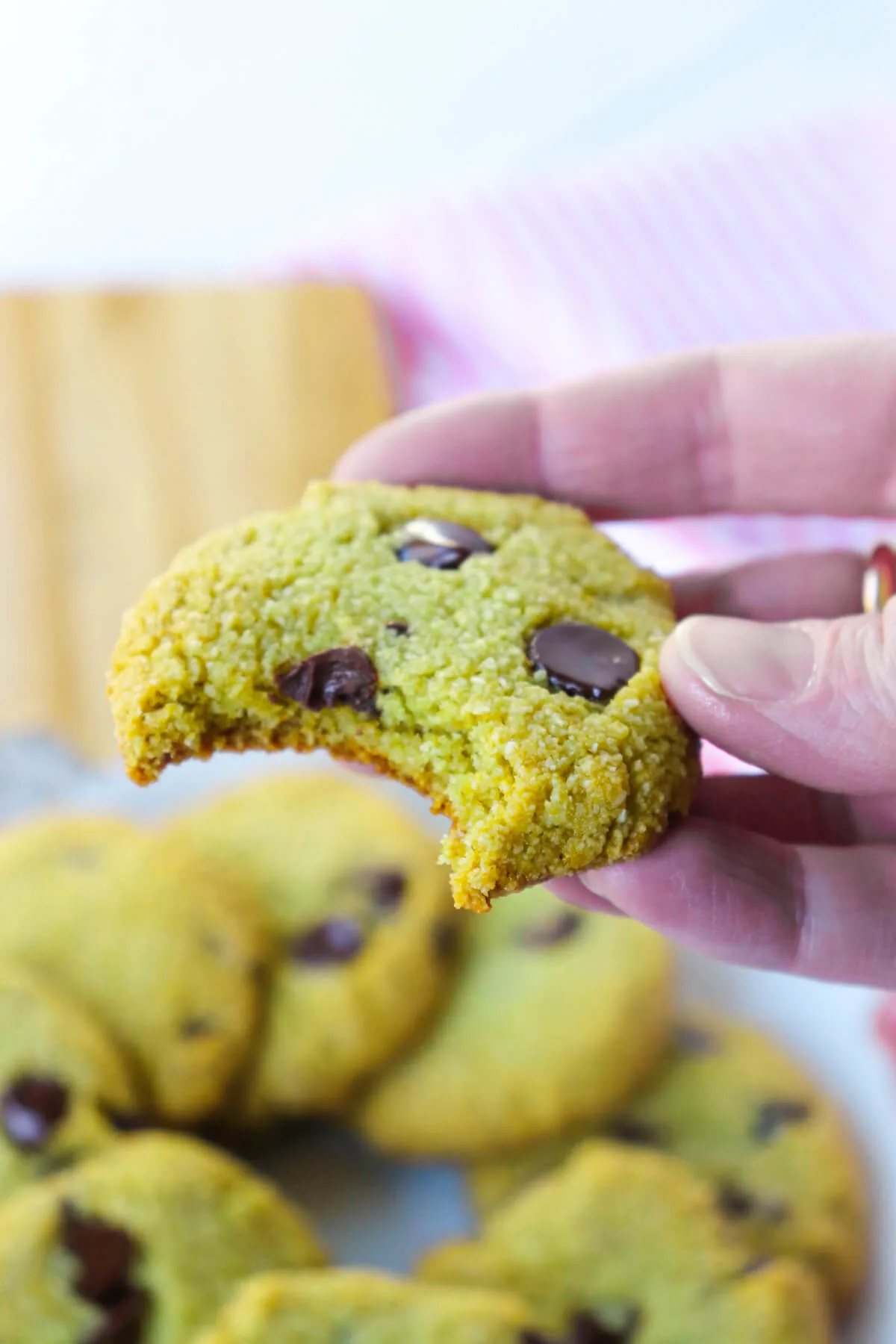 A hand holding up a gluten free matcha cookie with a bite taken out