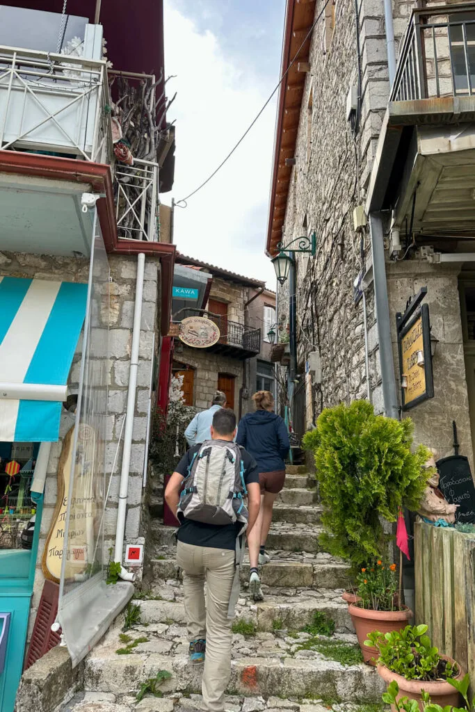 Walking up the stone steps between two stone buildings in Dimitsana