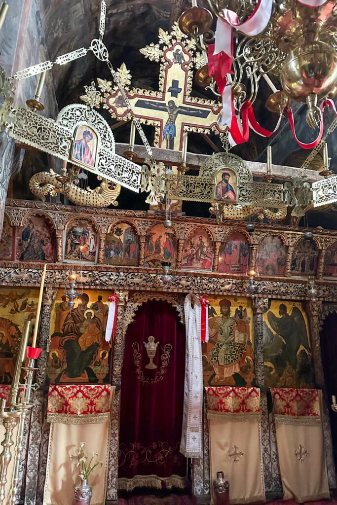 Inside of a Greek Orthodox Church on the Menalon Trail with a gold cross and icon decorated screen in front of the altar