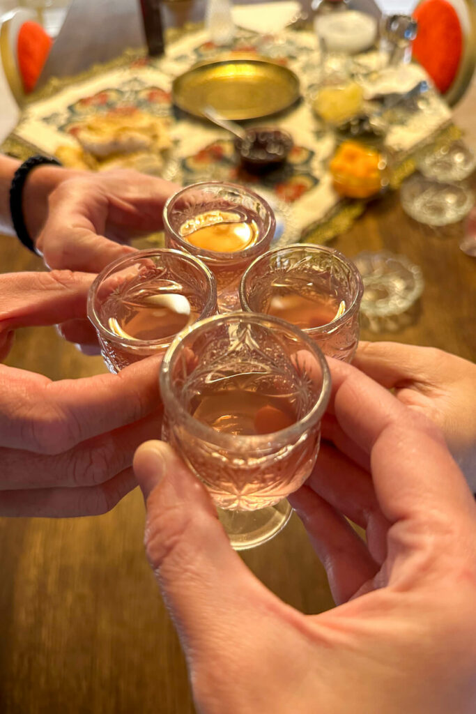 Four small glasses toasting with homemade Greek liqueur