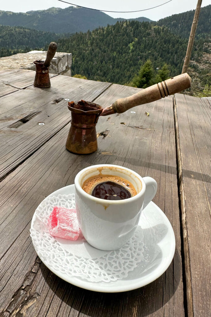 Greek coffee with a rose flavored sweet and a view of the mountains of Greece
