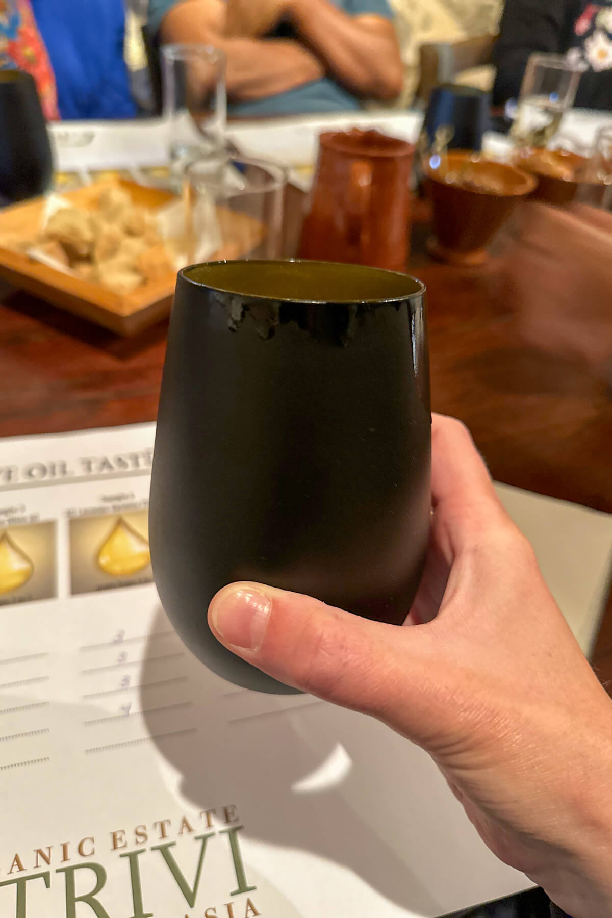 A cup held out with a hand used for the olive oil tasting