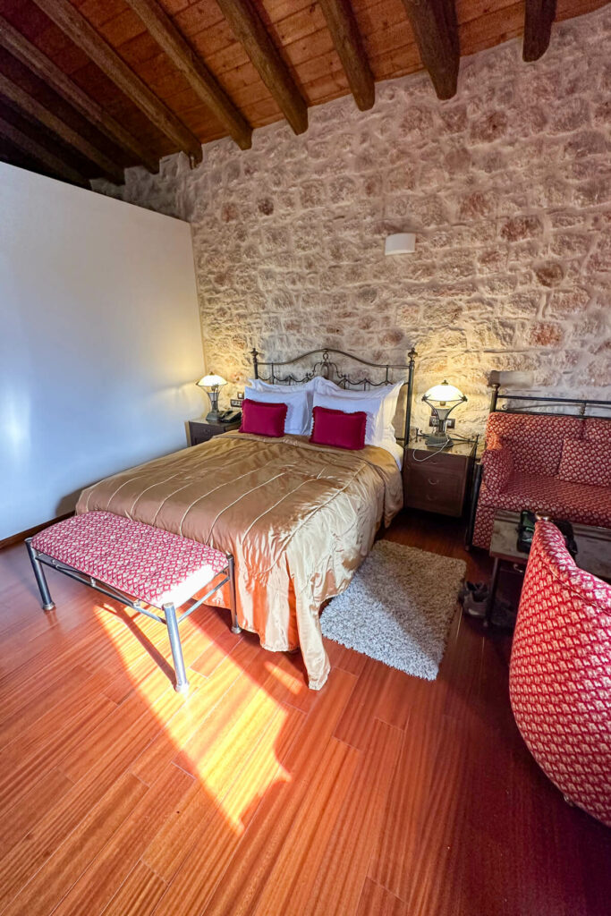 My room at the Mystras Resort and Spa with a red bed, stone wall, and wood flooring.