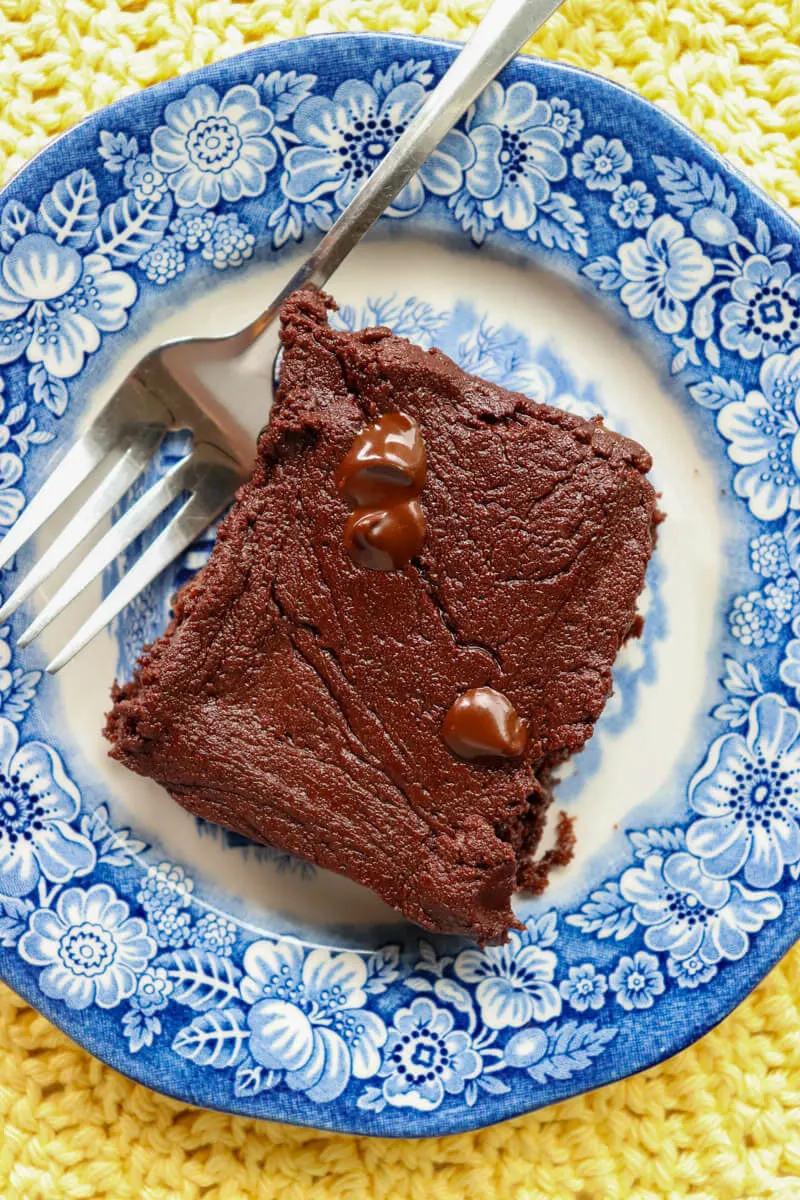 A keto zuccini brownie (low carb) on a blue and white plate with a fork next to it.