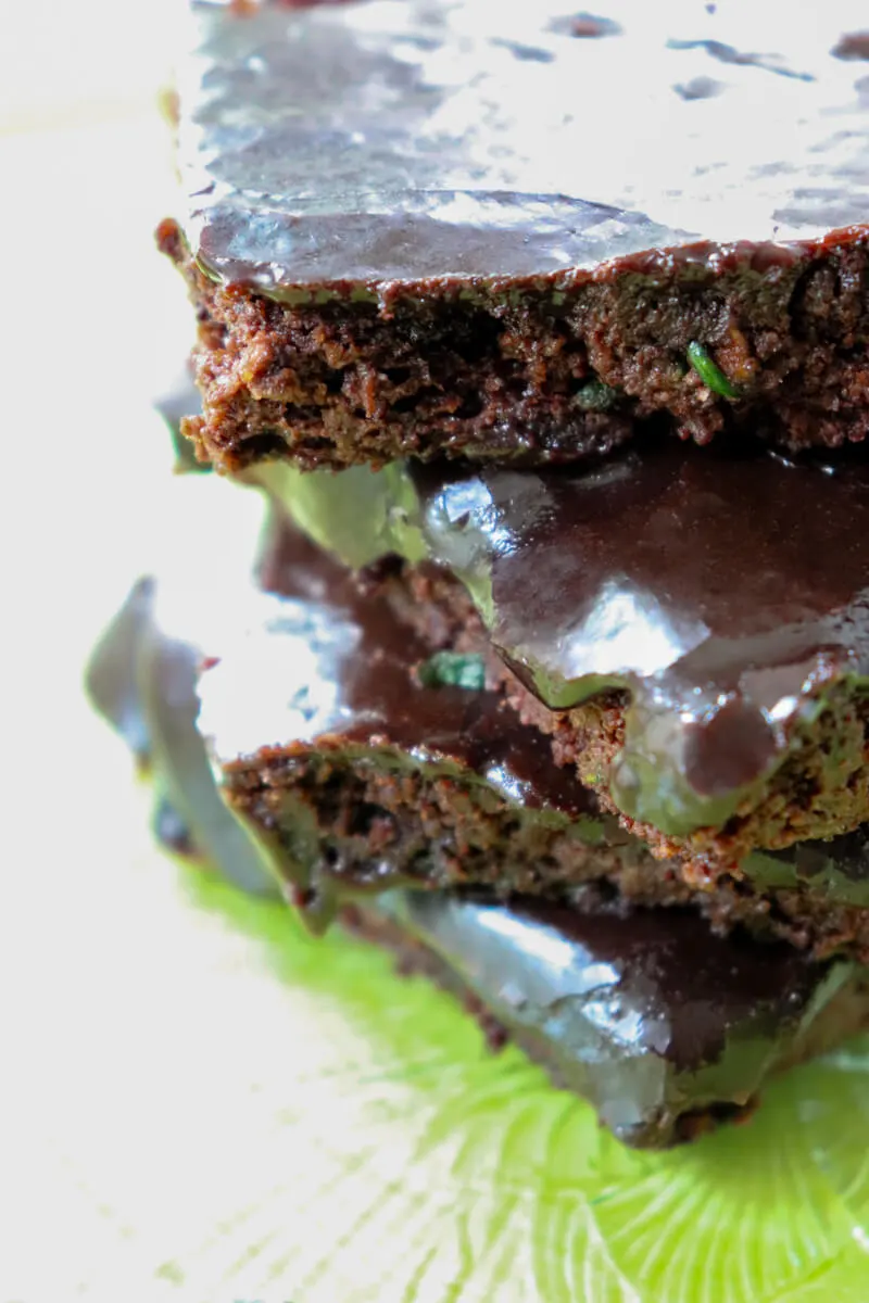 Stack of keto zucchini brownies on a clear plate on top of a green plate.