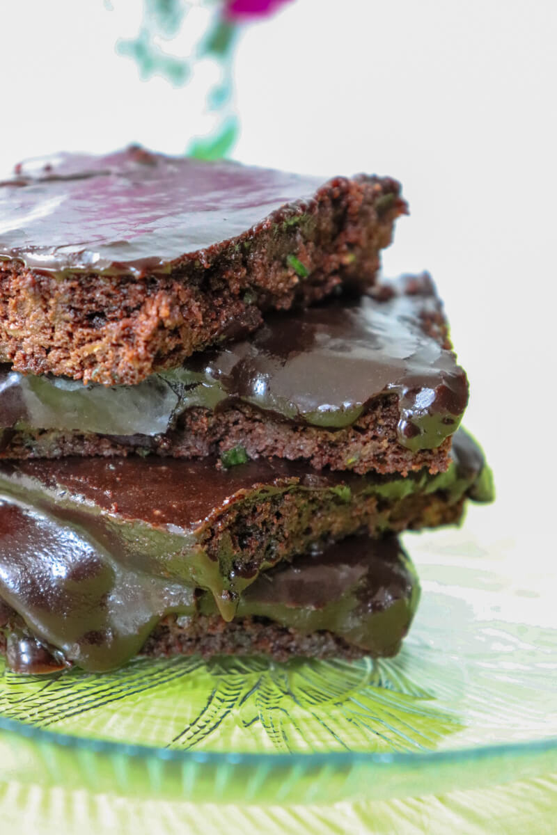 Stack of keto zucchini brownies on a clear plate on top of a green plate.