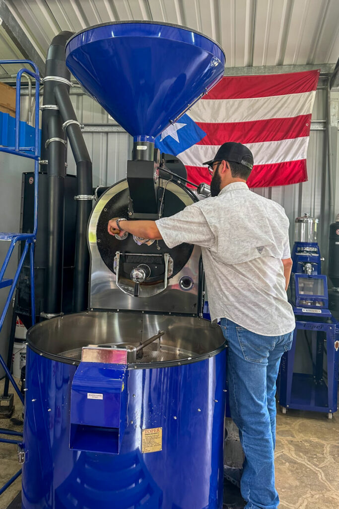 A man in front of a Puerto Rican flag releasing the roasted coffee beans from the roaster