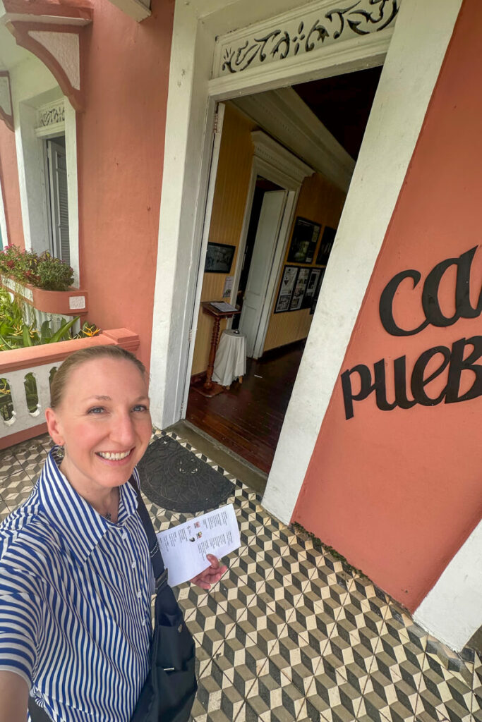 A woman in front of the pink and white front entrance to Casa Pueblo