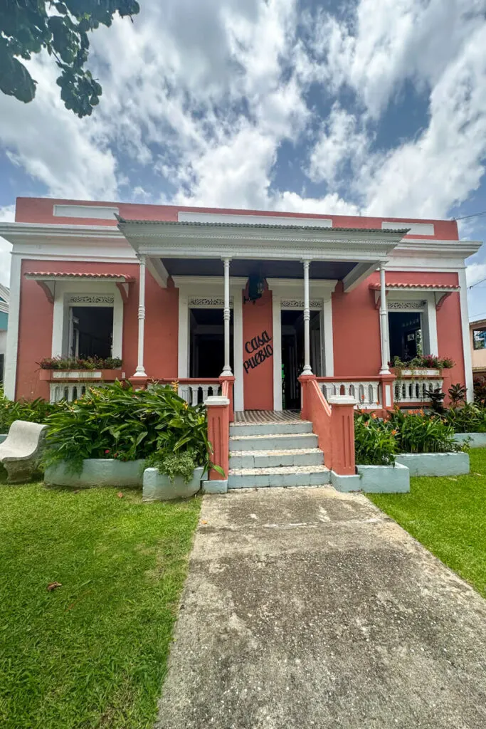 A front view of the pink and white Casa Pueblo with stairs leading up to the front door