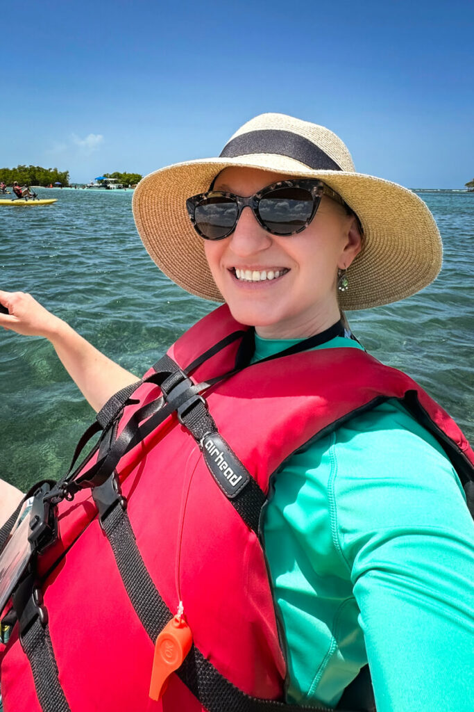 Close up of Explorer Momma wearing a life vest on a chili boat with water in the background