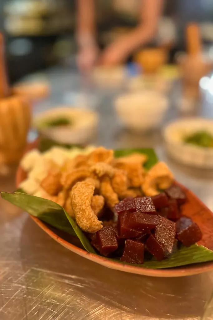 A dish with a banana leaf, chicharrones, guava jelly, and cheese.