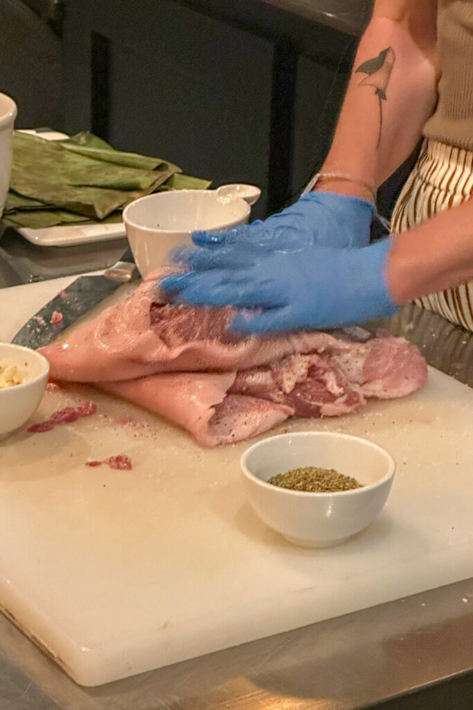 Lamb prepped and ready to marinate. Two blue gloved hands putting it in the pan.