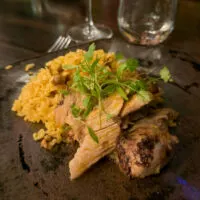 A plate of Puerto Rican authentic food, pork, rice, and pasteles.