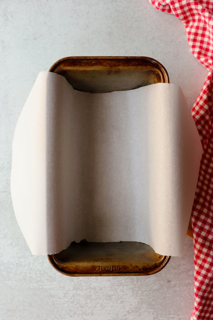 Overhead view of a loaf pan with a sheet of parchment paper over it