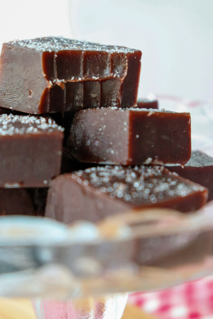 A bite taken out of the top piece of keto fudge in a stack on a glass plate