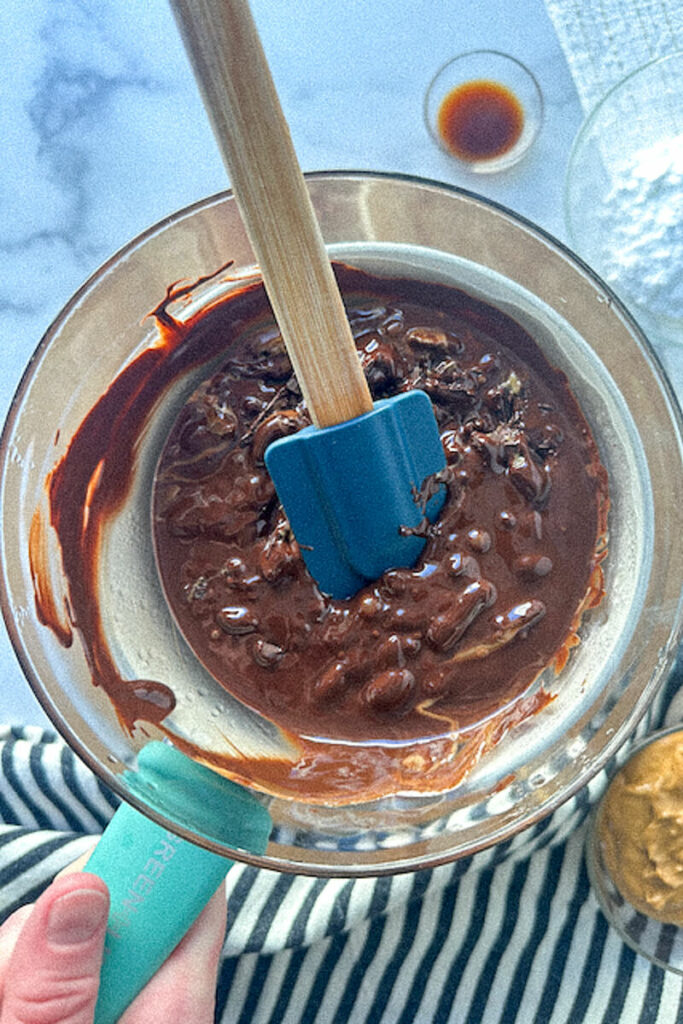 Overhead view of a glass bowl of melting chocolate with a spatula in it