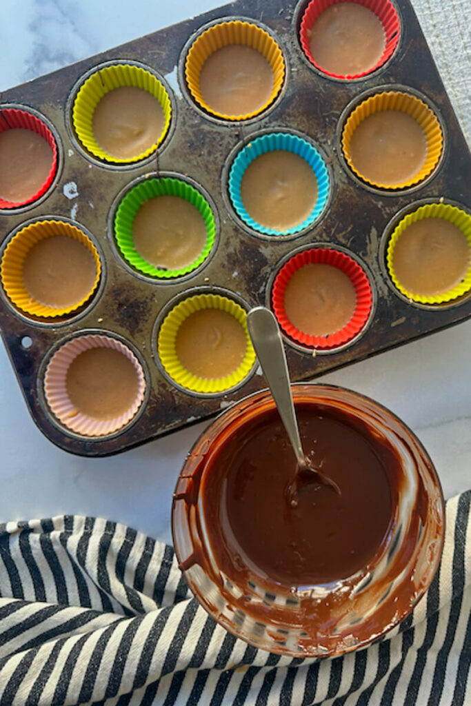 Overhead view of a bowl of chocolate next to cups with chocolate and peanut butter layers