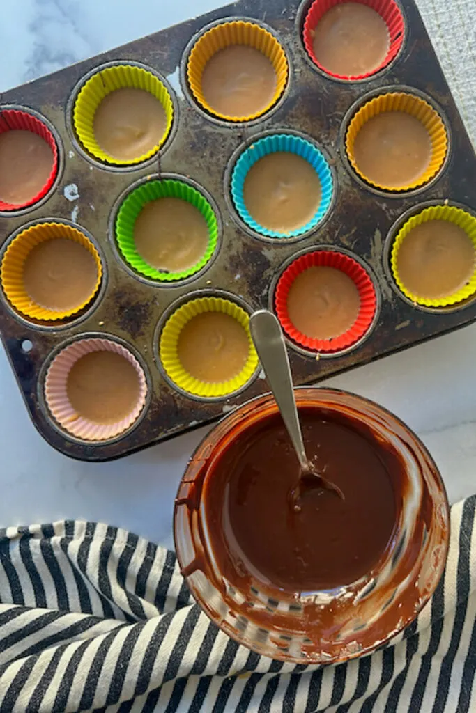 Overhead view of a bowl of chocolate next to cups with chocolate and peanut butter layers