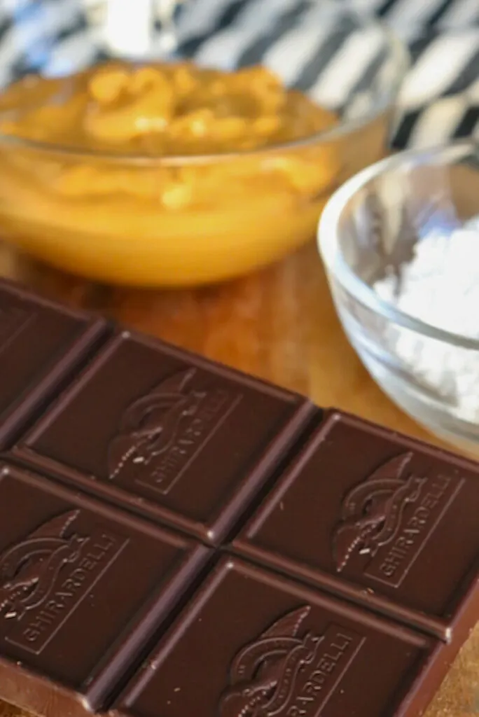 A close up view of unsweetened chocolate, a bowl of peanut butter and another of sweetener