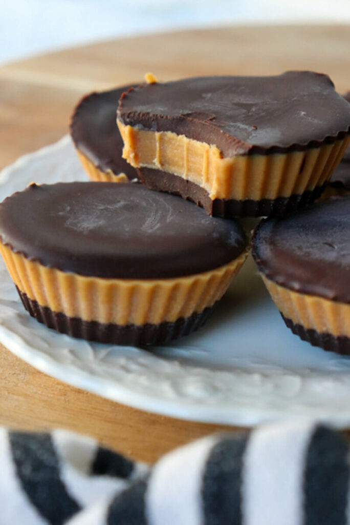 A stack of keto peanut butter cups with a bite taken out on a white plate