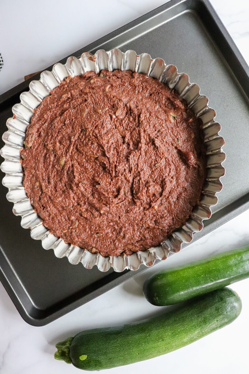 Overhead view of a baked keto chocolate zucchini cake, still in the fluted metal pan.