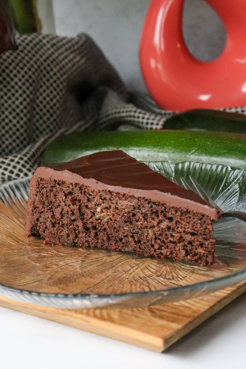 A piece of keto chocolate zucchini cake on a decorative glass plate.