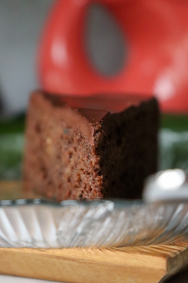A piece of keto chocolate zucchini cake on a decorative glass plate.