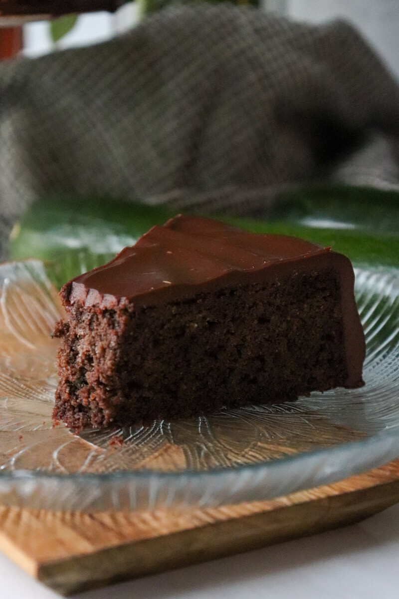 A bite taken out of a piece of keto chocolate zucchini cake on a decorative glass plate.