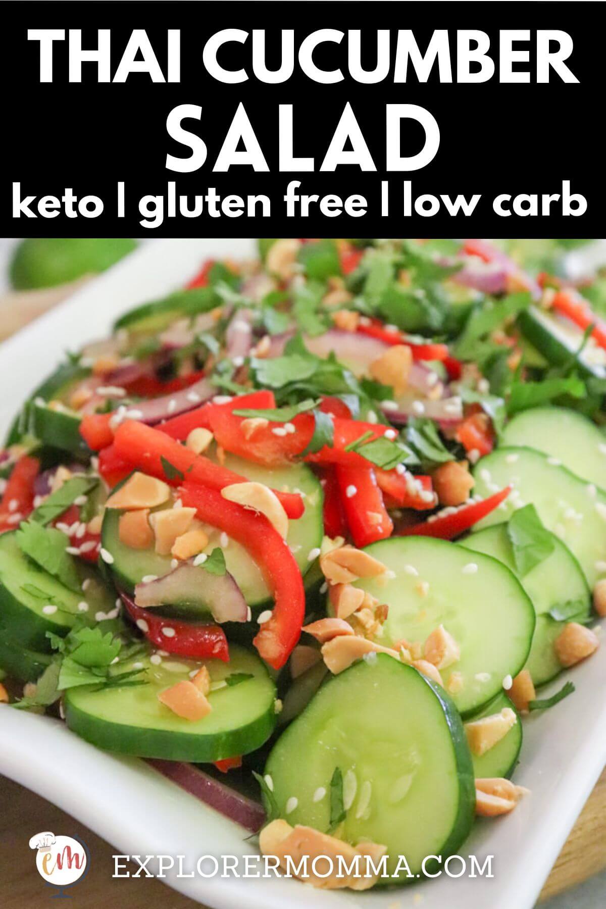 A white rectangle platter of Thai cucumber salad with cucumbers, red peppers, and red onion, dotted with sesame seeds and cilantro.