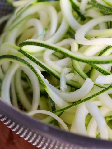 A metal colander with spiralized zucchini noodles