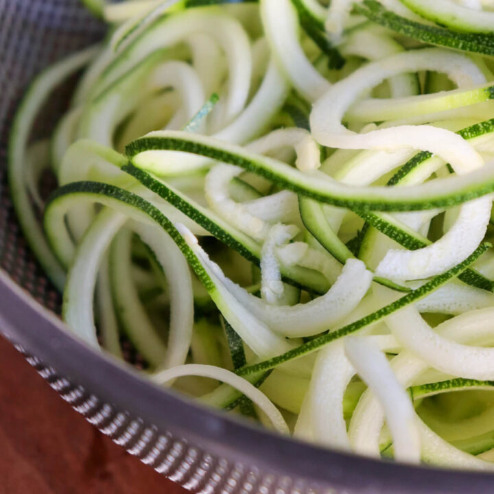 A metal colander with spiralized zucchini noodles