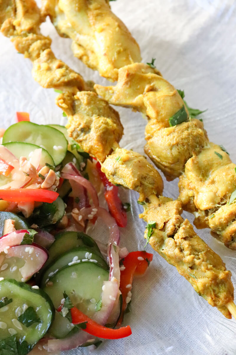 Two skewers of chicken satay with Thai cucumber salad