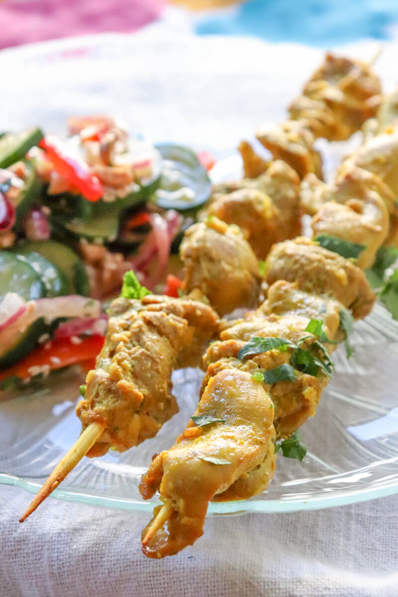 Two skewers of chicken satay with Thai cucumber salad