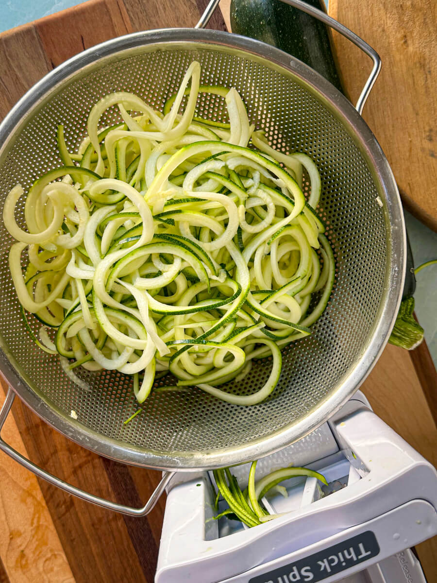 Overhead view of a metal bowl of spiralized zucchini noodles