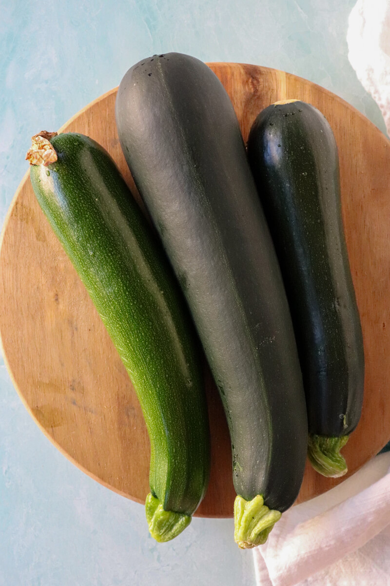 Overhead view of 3 zucchinis on a wooden board