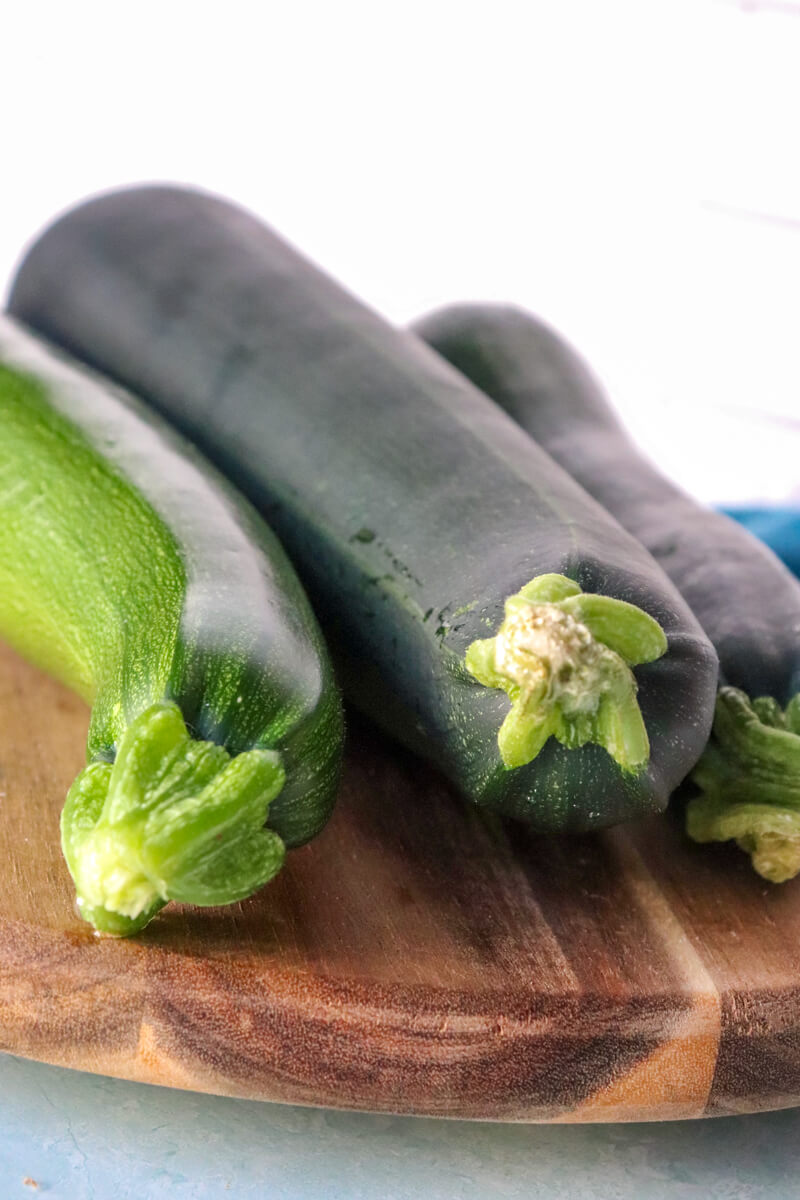 Front view of 3 zucchinis on a wooden board