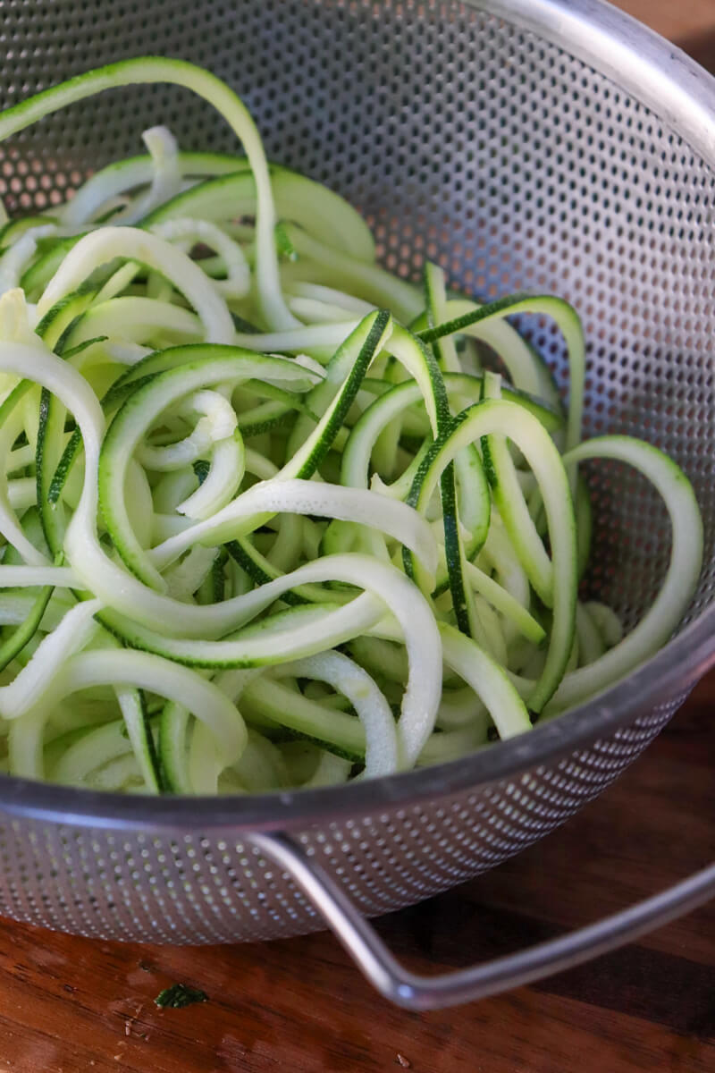 A metal colander with spiralized zucchini noodles