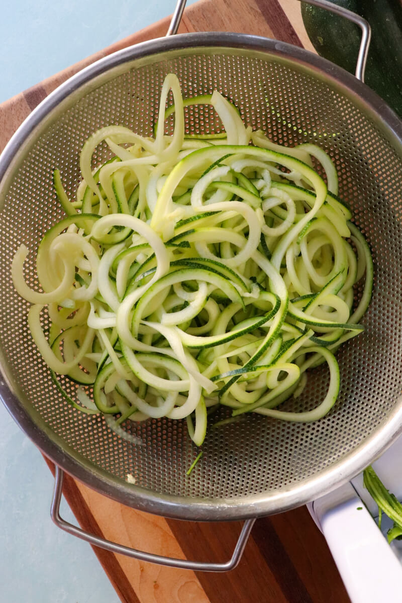 Overhead view of metal colander with spiralized zucchini noodles