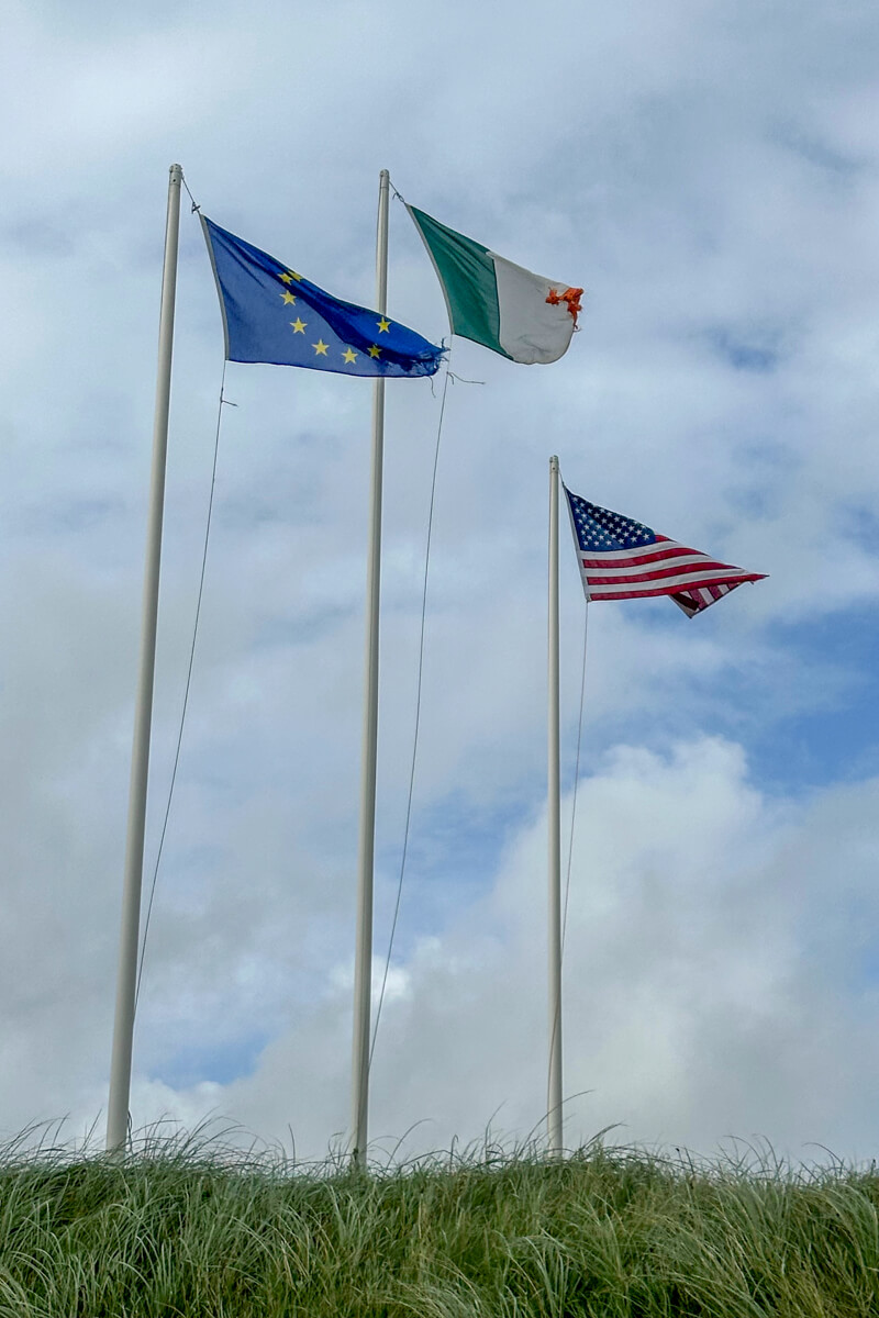 Three flag poles with the flag of Ireland, European Union, and US flying