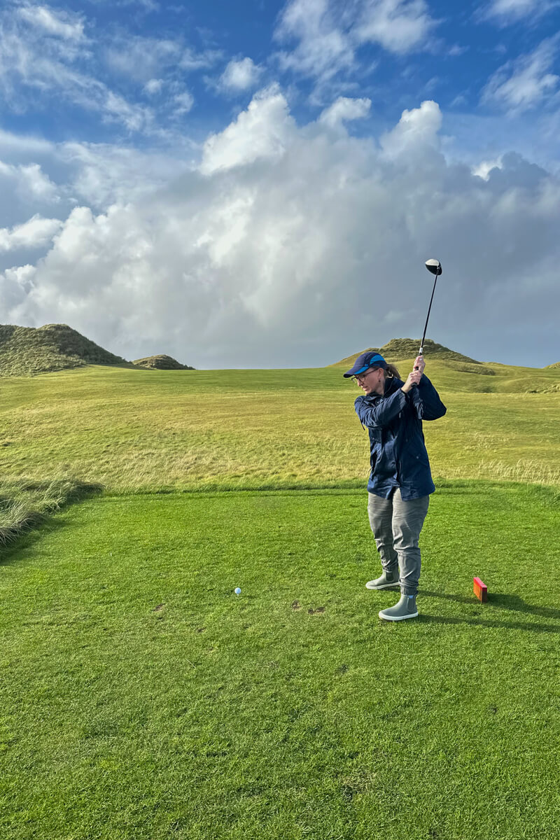Lauren with a club in the air teeing off at Carne Golf Links