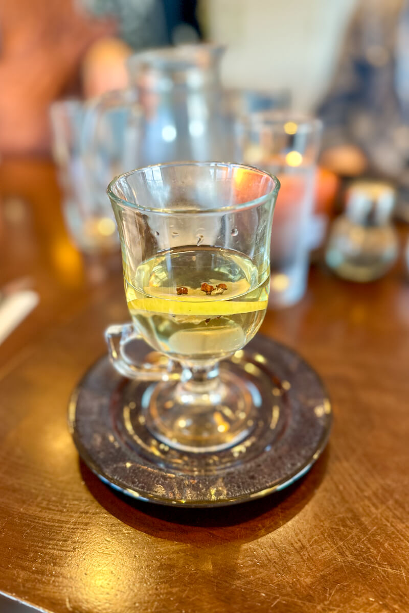 A front view of the clear glass hot whiskey with lemon and cloves given to me after the downpour on the golf course