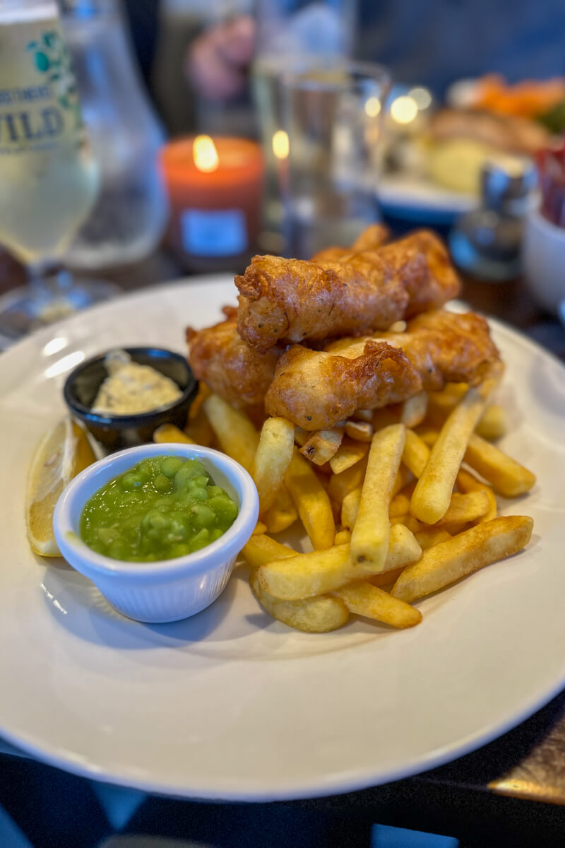 A front view of my fish and chips with a small white ceramic bowl of mushy peas