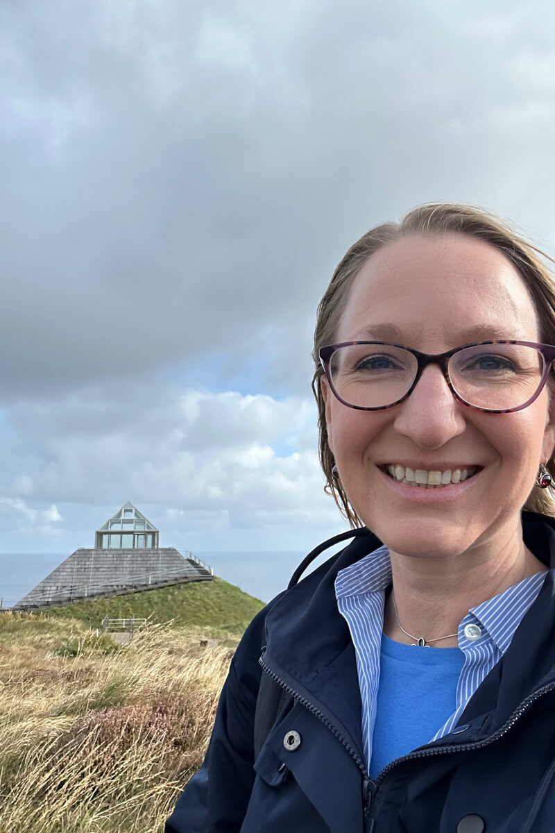 A face view of Lauren in front of the triangular visitor centre at Ceide Fields, Mayo, Ireland