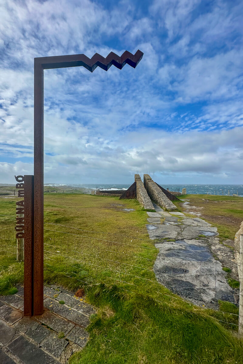 Dún a mBo sign and view of a structure and the Atlantic Ocean.