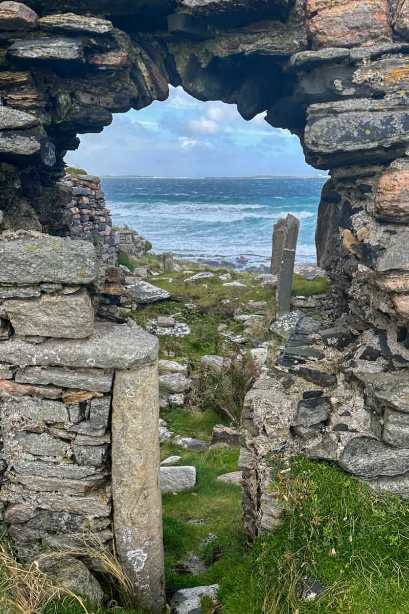 View through a stone wall of Cross Abbey at Cross Cemetery.