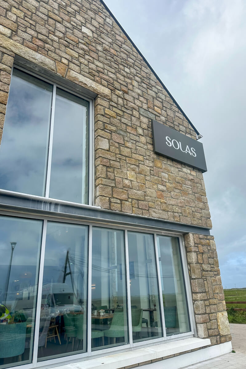 A shot of the front of the Solas Visitor Center with large windows and a light stone wall.