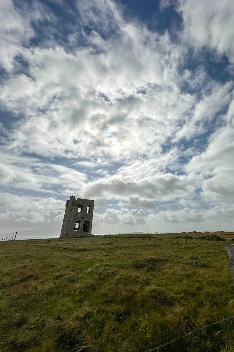 A view with Glosh Tower in the distance in Letterbeg, Ireland on a hill with clouds in the background.