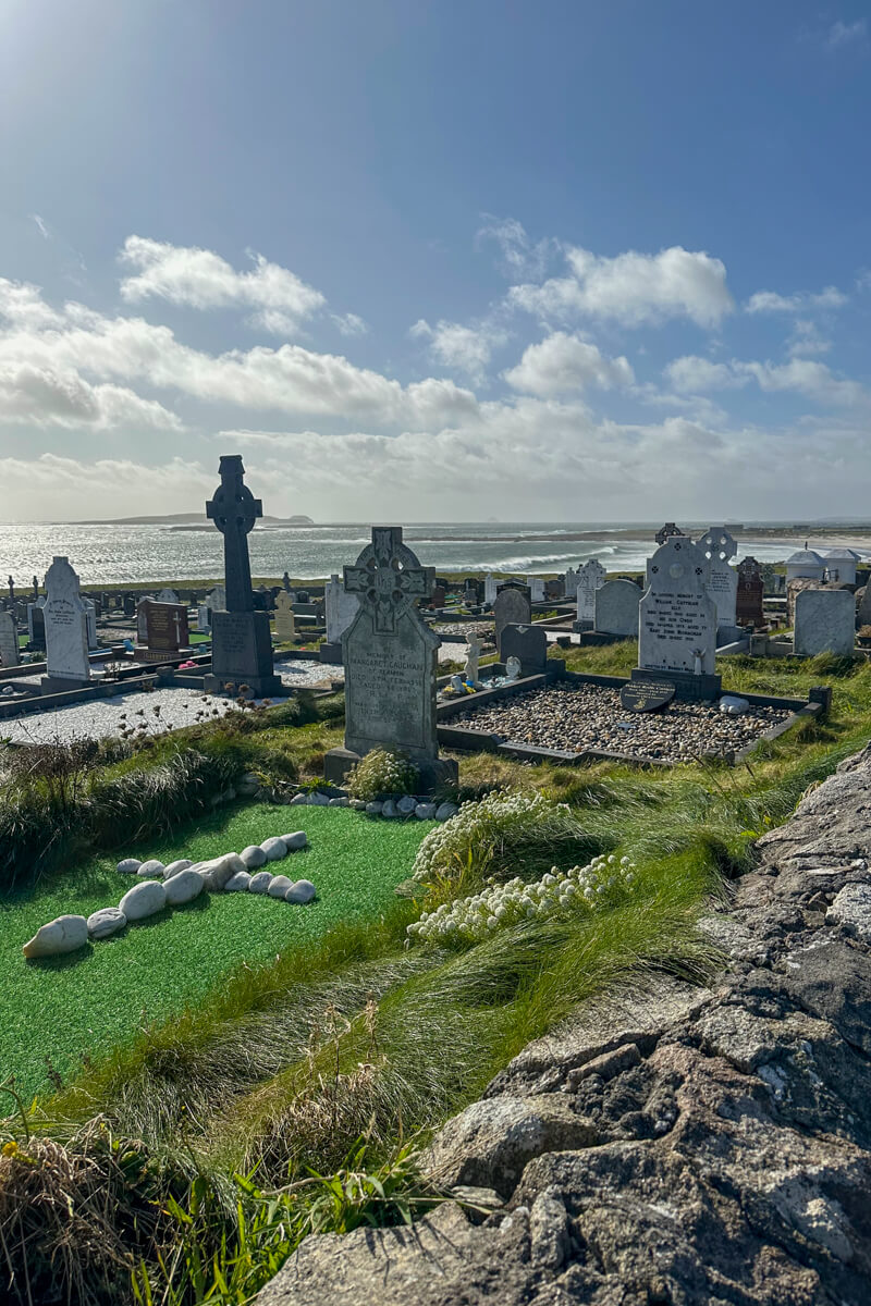 Cemetery in Fallmore, Ireland with Celtic crosses and a view of the beach and Atlantic Ocean in the background.